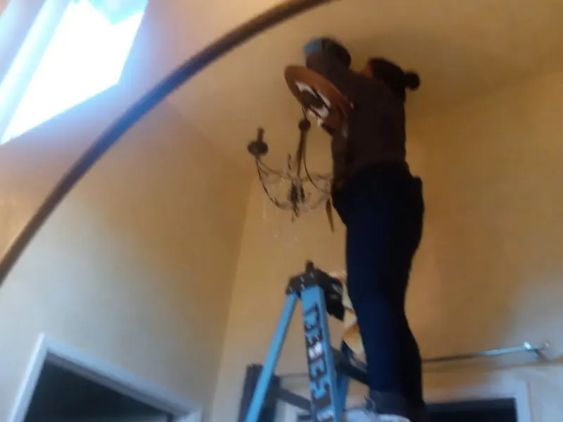 Electrician installing a chandelier in a Alamo residence